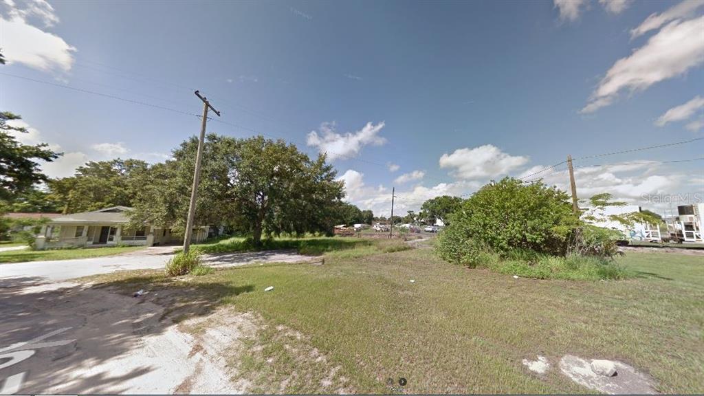 A grassy vacant lot sits next to a single-story house under a blue sky — 60 E STREET, LAKE WALES, FL