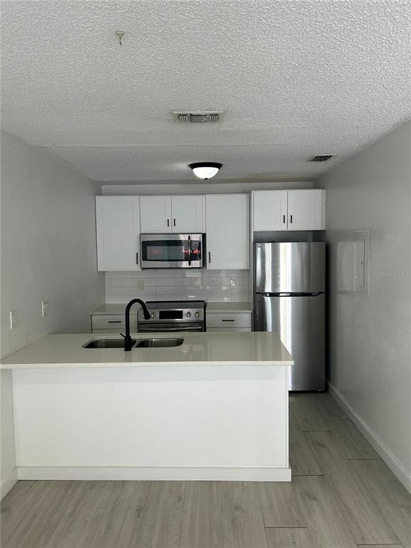 A kitchen features white cabinets, stainless steel appliances, a breakfast bar, and light wood flooring — 2955 SE 53RD COURT UNIT C, OCALA, FL