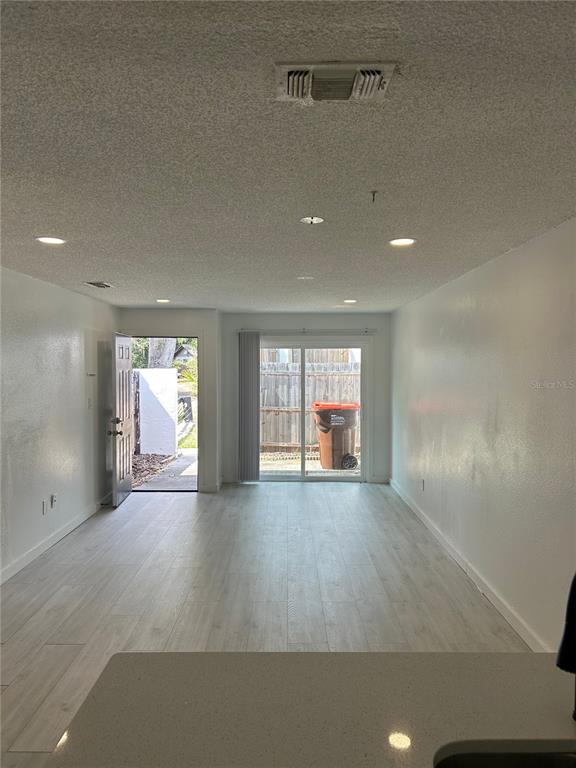 An interior view of a room with light wood-look flooring, recessed lighting, and a sliding door — 2955 SE 53RD COURT UNIT C, OCALA, FL