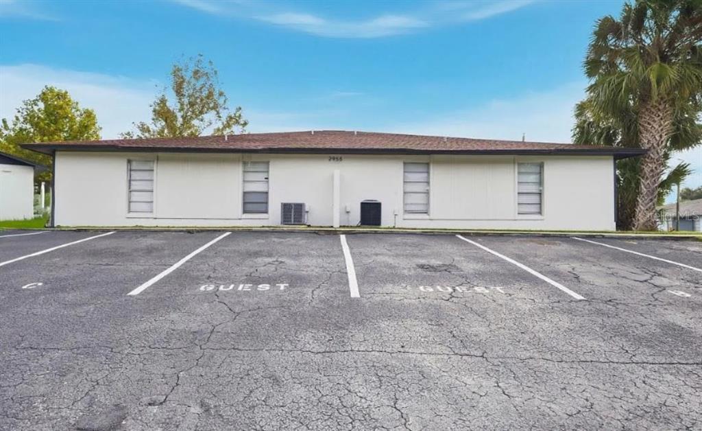 A single-story building with a white exterior and four windows faces a paved parking lot — 2955 SE 53RD COURT UNIT C, OCALA, FL