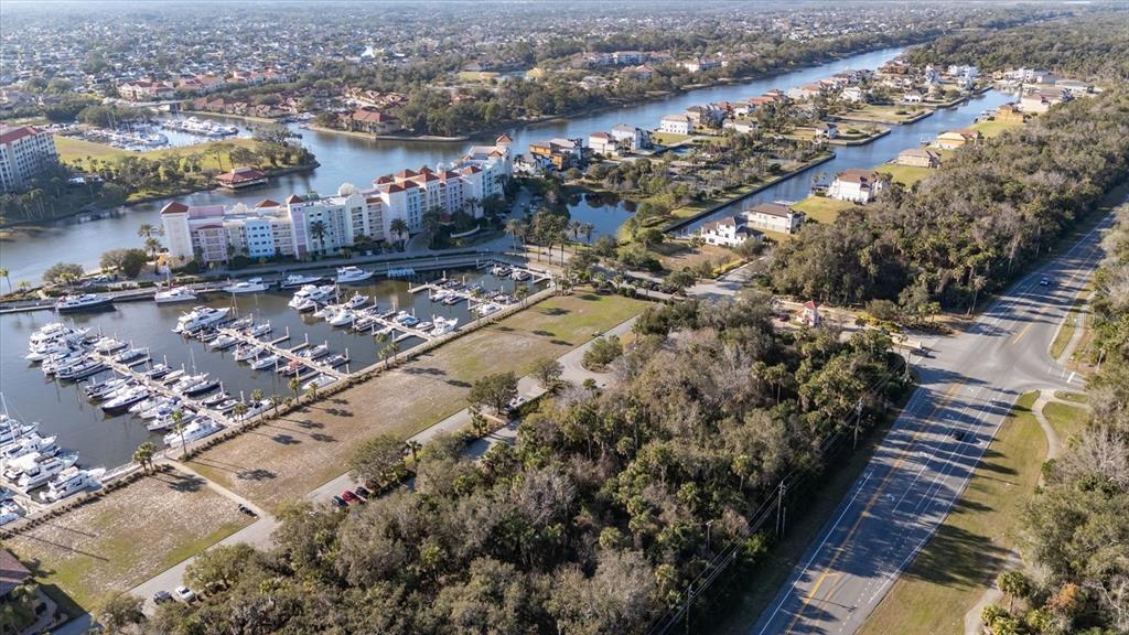 An aerial view shows a marina with docked boats next to a large residential complex — 100 HARBOR VILLAGE POINT S, PALM COAST, FL