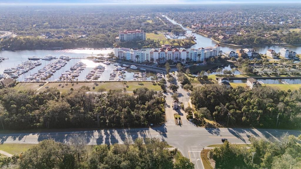 An aerial view shows a marina with many boats, large residential buildings, and surrounding greenery — 100 HARBOR VILLAGE POINT S, PALM COAST, FL
