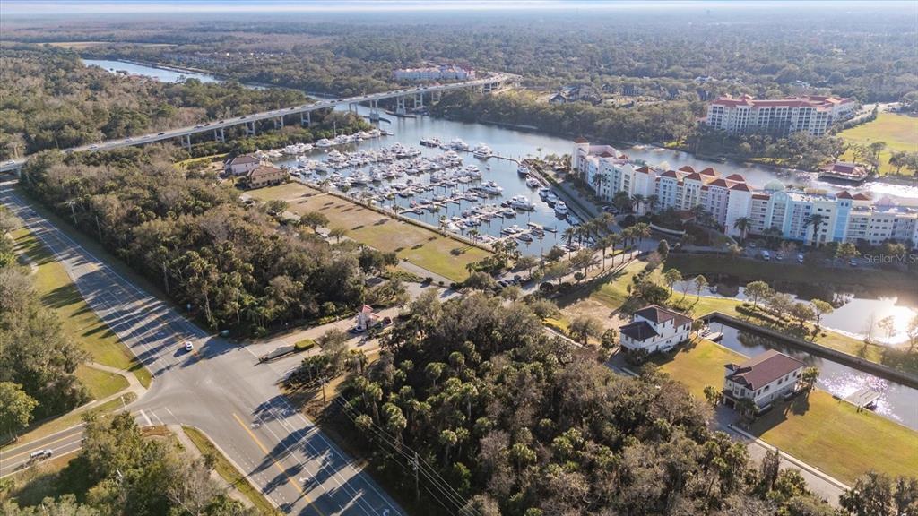 An aerial view shows a marina with many boats, a bridge, and nearby residential buildings — 100 HARBOR VILLAGE POINT S, PALM COAST, FL
