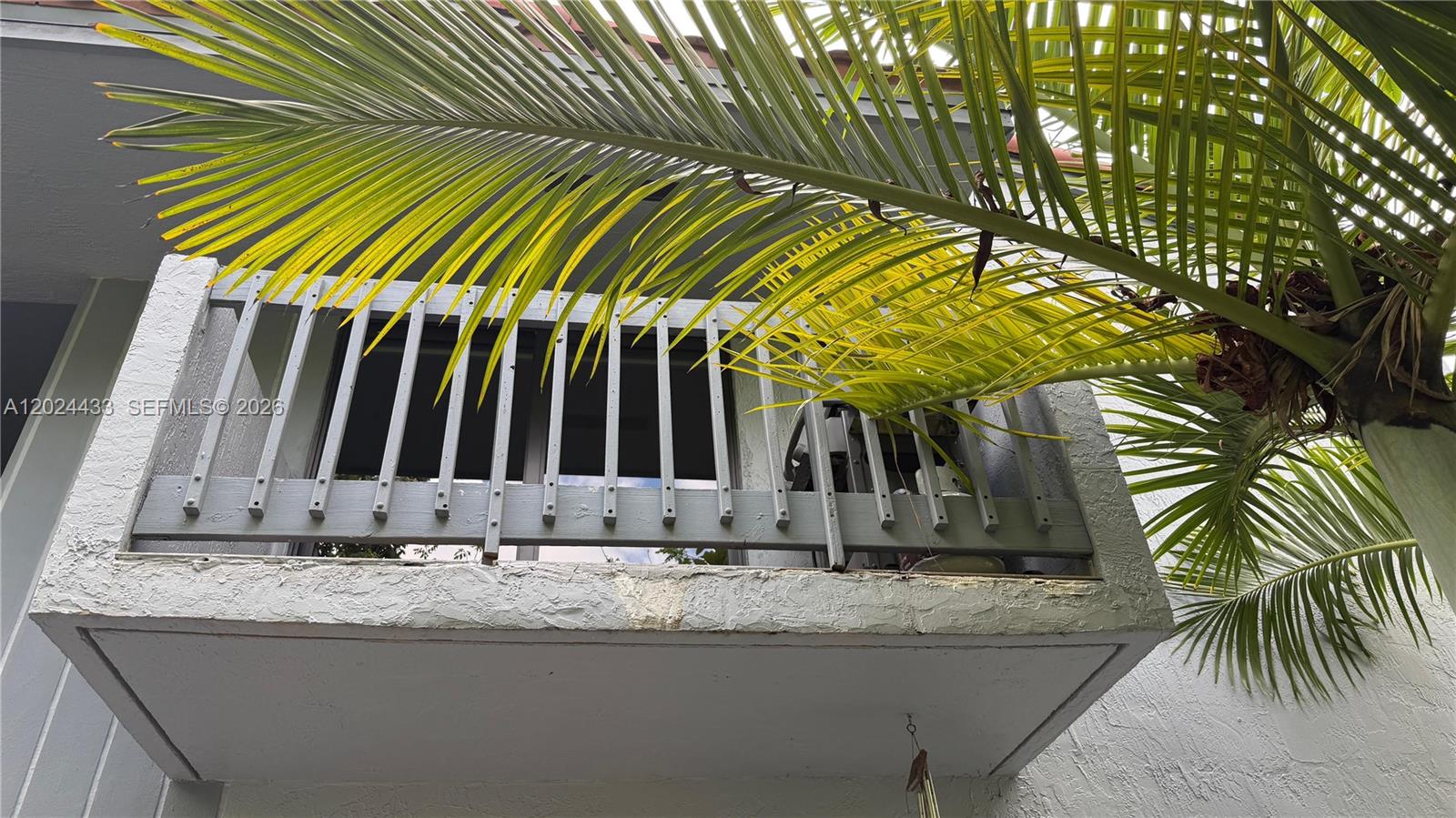 A low-angle view of a concrete balcony with a gray railing and a palm tree — 13675 SW 62nd St # 3, Miami FL 33183, MIAMI, FL