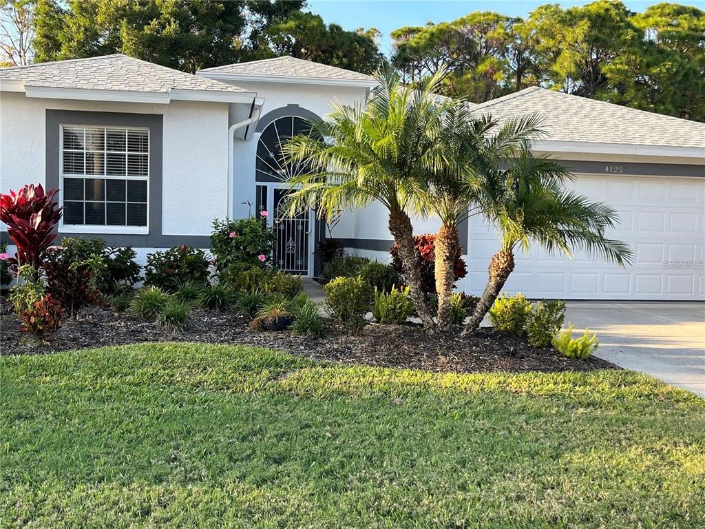 A single-story house with a white exterior, gray trim, palm trees, and a two-car garage — 4122 WESTBOURNE CIRCLE, SARASOTA, FL