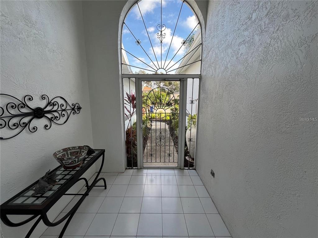 An entryway features white tile flooring, a decorative wall scroll, a console table, and a screen door — 4122 WESTBOURNE CIRCLE, SARASOTA, FL