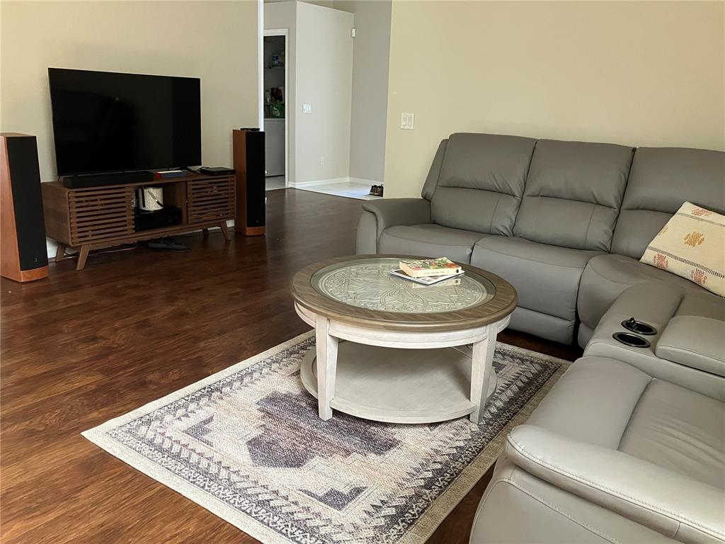 A living room features a grey sectional sofa, a round coffee table, and a television console — 4122 WESTBOURNE CIRCLE, SARASOTA, FL