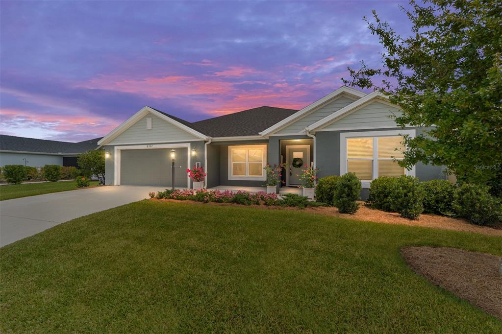 A single-story house with a gray exterior, two-car garage, and a landscaped front lawn — 6557 MCKNIGHT LOOP, THE VILLAGES, FL