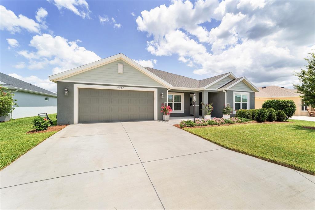A single-story house with a two-car garage, gray siding, and a concrete driveway — 6557 MCKNIGHT LOOP, THE VILLAGES, FL