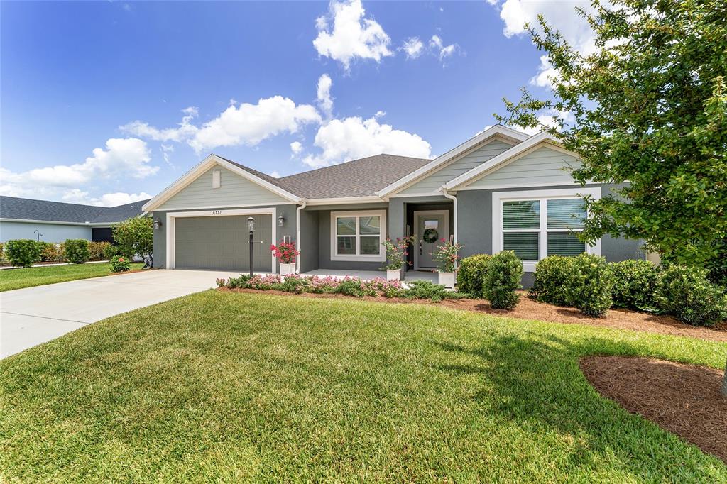 A single-story house with a gray exterior, a two-car garage, and a landscaped front lawn — 6557 MCKNIGHT LOOP, THE VILLAGES, FL