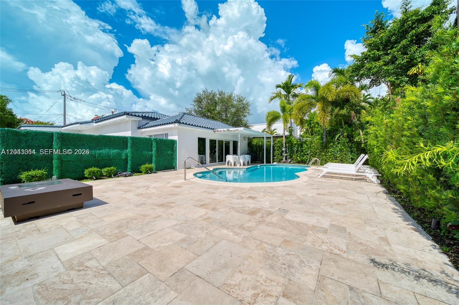 A backyard features a swimming pool, stone patio, lounge chairs, and a green privacy fence — 2298 SW 16th Ave, Miami FL 33145, MIAMI, FL