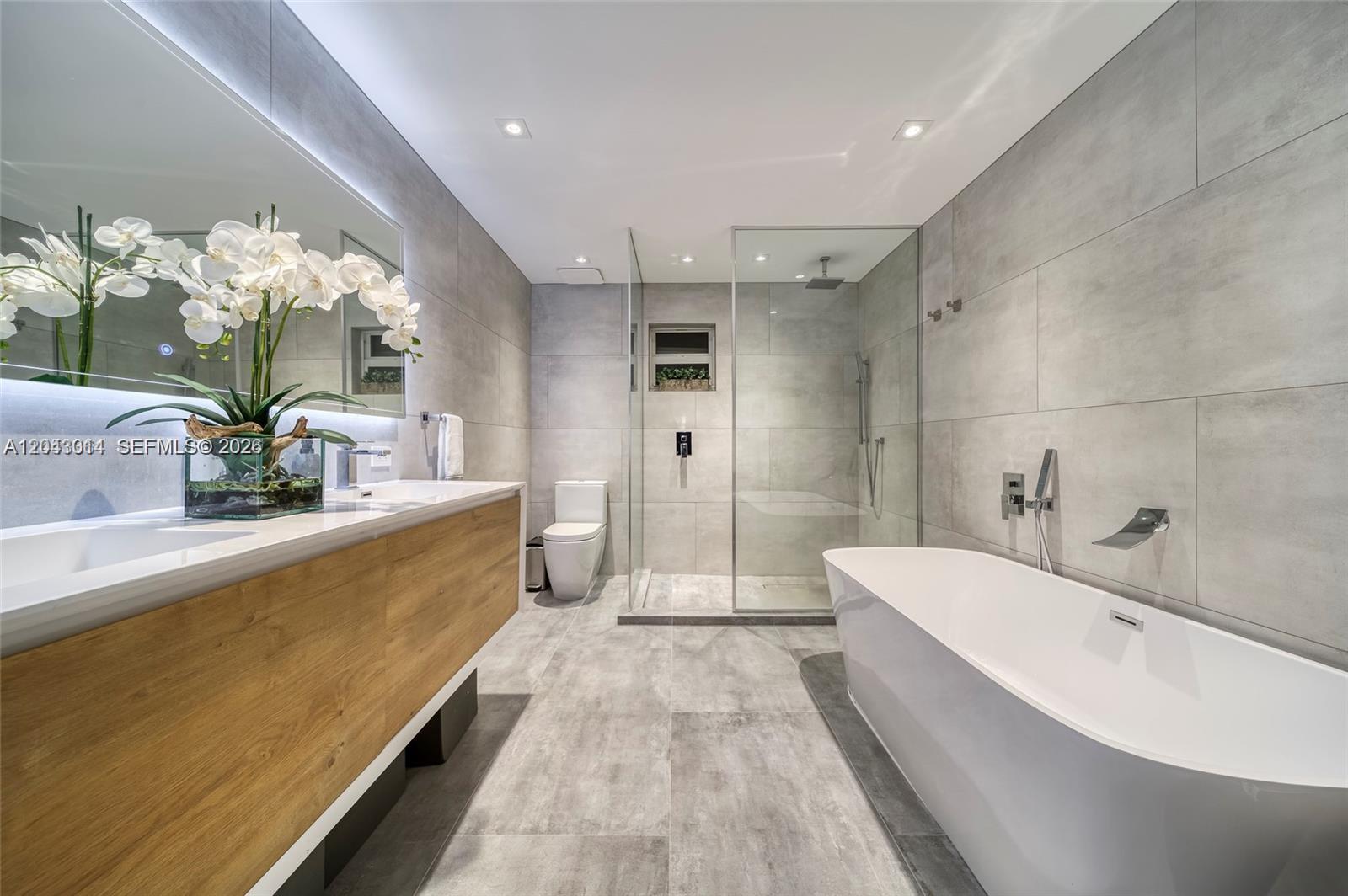 A modern bathroom features a floating wood vanity, a glass-enclosed shower, and a freestanding tub — 2298 SW 16th Ave, Miami FL 33145, MIAMI, FL