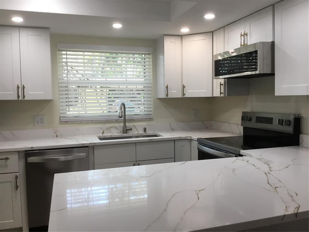 A kitchen with white cabinets, stainless steel appliances, and white marble-look countertops — 44 COUNTRY CLUB DRIVE UNIT 44, LARGO, FL