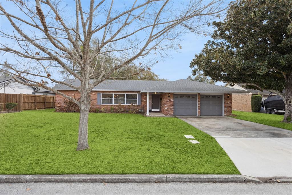 A single-story brick house features a gray shingled roof, two garage doors, and a lawn — 2504 LAUDERDALE COURT, ORLANDO, FL