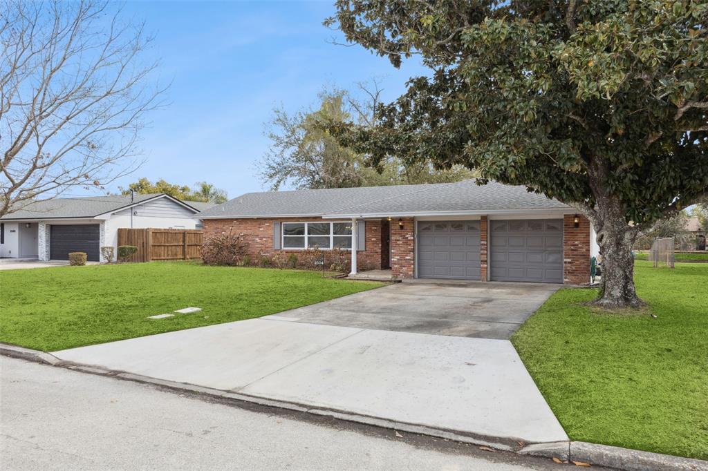 A single-story brick house features a two-car garage, a concrete driveway, and a large tree — 2504 LAUDERDALE COURT, ORLANDO, FL