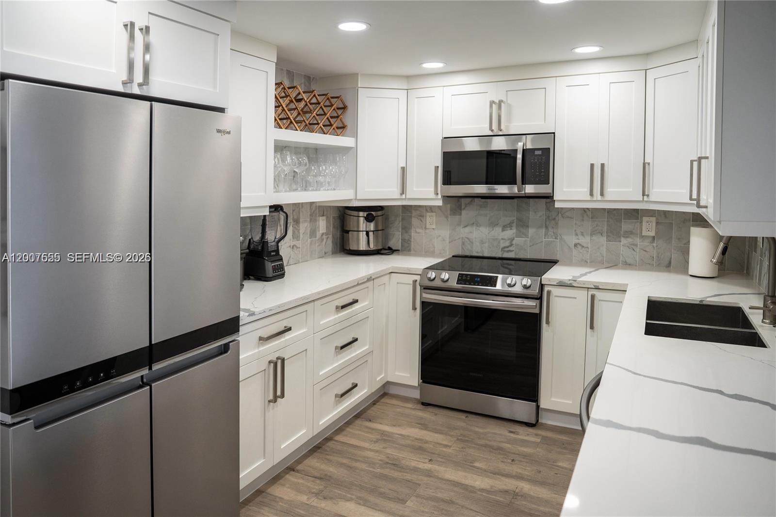 A modern kitchen features white cabinets, stainless steel appliances, and marble-patterned countertops and backsplash — 1600 S Ocean Dr # 17D, Hollywood FL 33019, HOLLYWOOD, FL