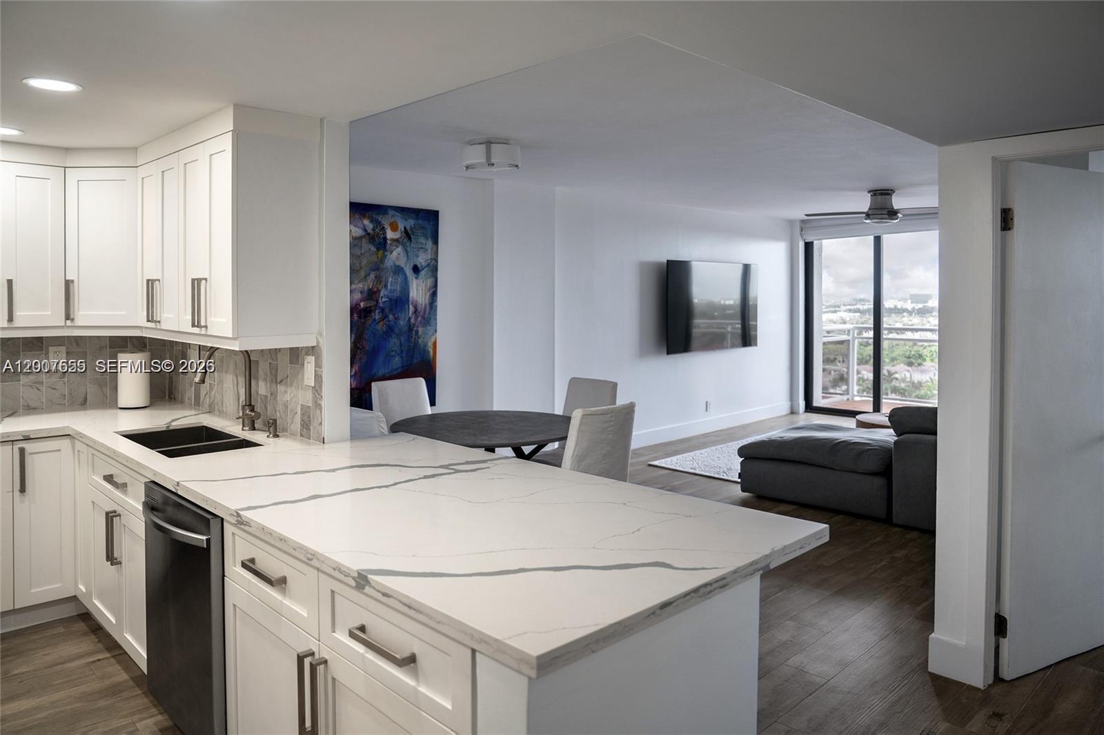 A modern kitchen with white cabinets and quartz countertops opens into a living area — 1600 S Ocean Dr # 17D, Hollywood FL 33019, HOLLYWOOD, FL