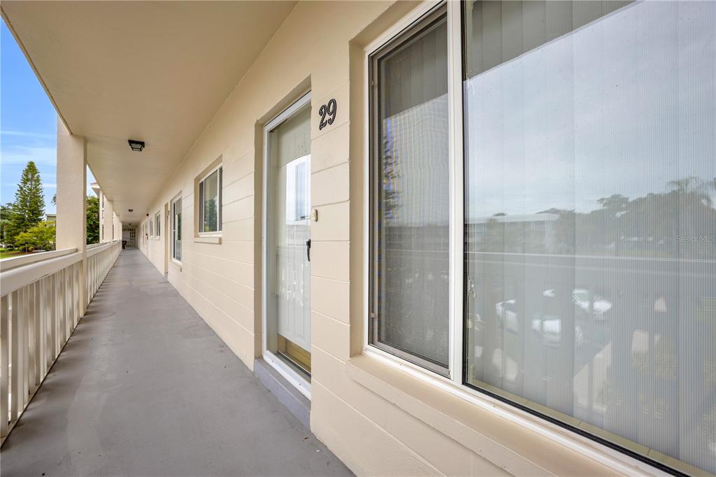 An exterior walkway with a white railing leads past a door labeled 29 — 2451 CANADIAN WAY UNIT 29, CLEARWATER, FL