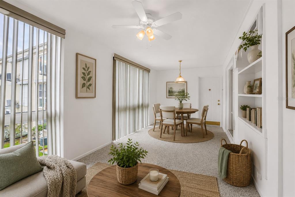 A bright dining and living area features a round table, ceiling fan, and built-in shelving — 2451 CANADIAN WAY UNIT 29, CLEARWATER, FL