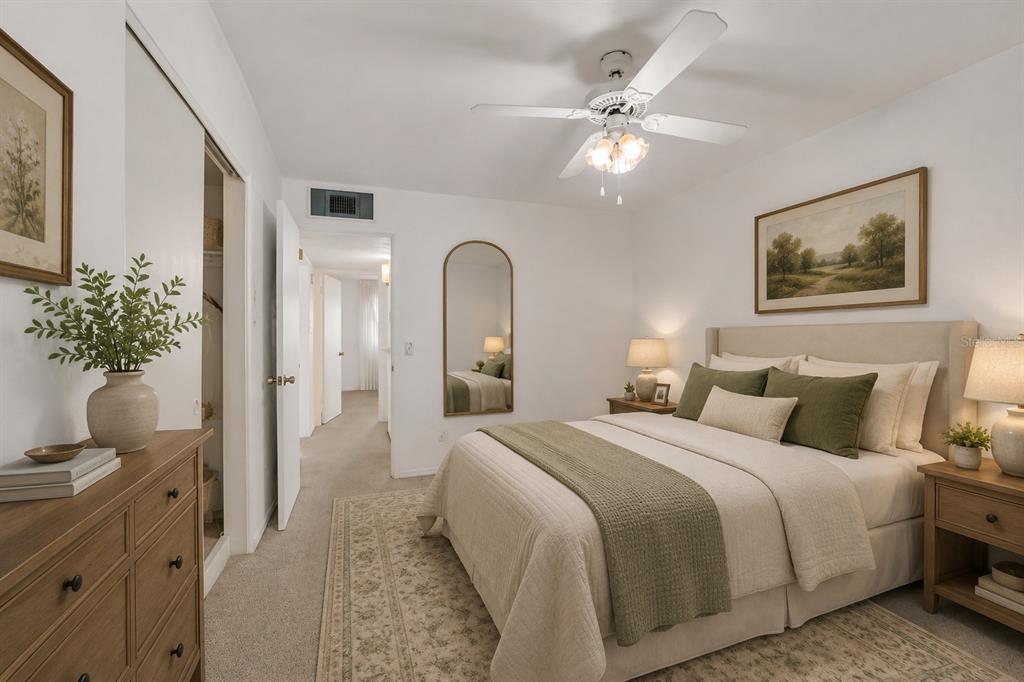 A bedroom features a queen bed, wooden dresser, arched floor mirror, and a ceiling fan — 2451 CANADIAN WAY UNIT 29, CLEARWATER, FL