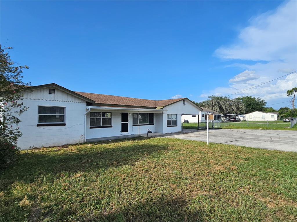A single-story white house with a brown shingled roof and a large concrete driveway — 2302 BURNS STREET, LAKELAND, FL