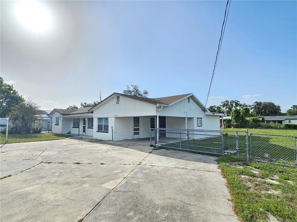 A single-story white house with a concrete driveway and a chain-link fenced yard — 2302 BURNS STREET, LAKELAND, FL