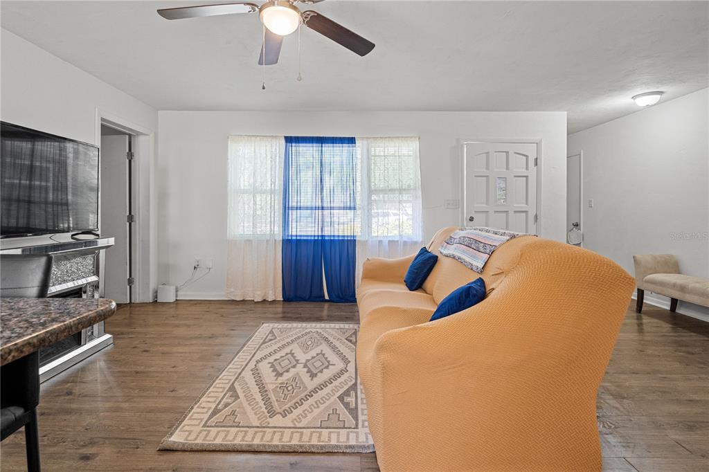 A living room features wood-look flooring, a ceiling fan, a sofa, and a window — 1009 SE 20TH STREET, GAINESVILLE, FL
