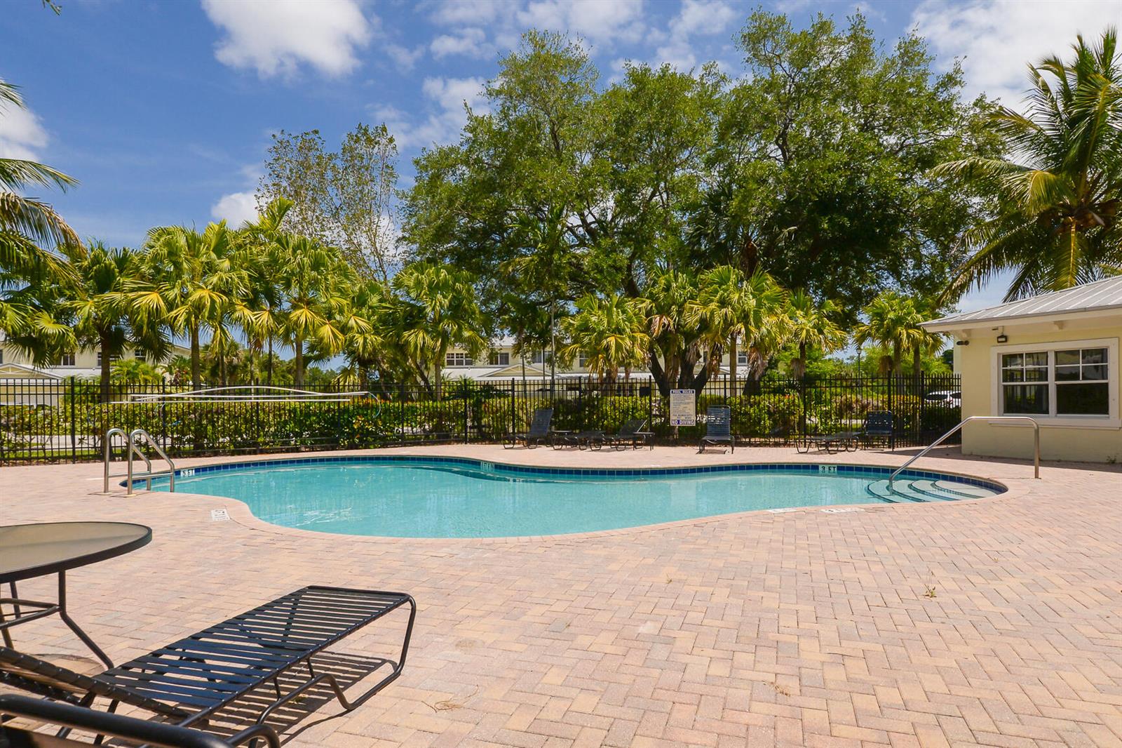 A swimming pool with a brick patio, lounge chairs, and palm trees under a blue sky — 3902 Sabal Way, Fort Pierce FL 34981, FORT PIERCE, FL