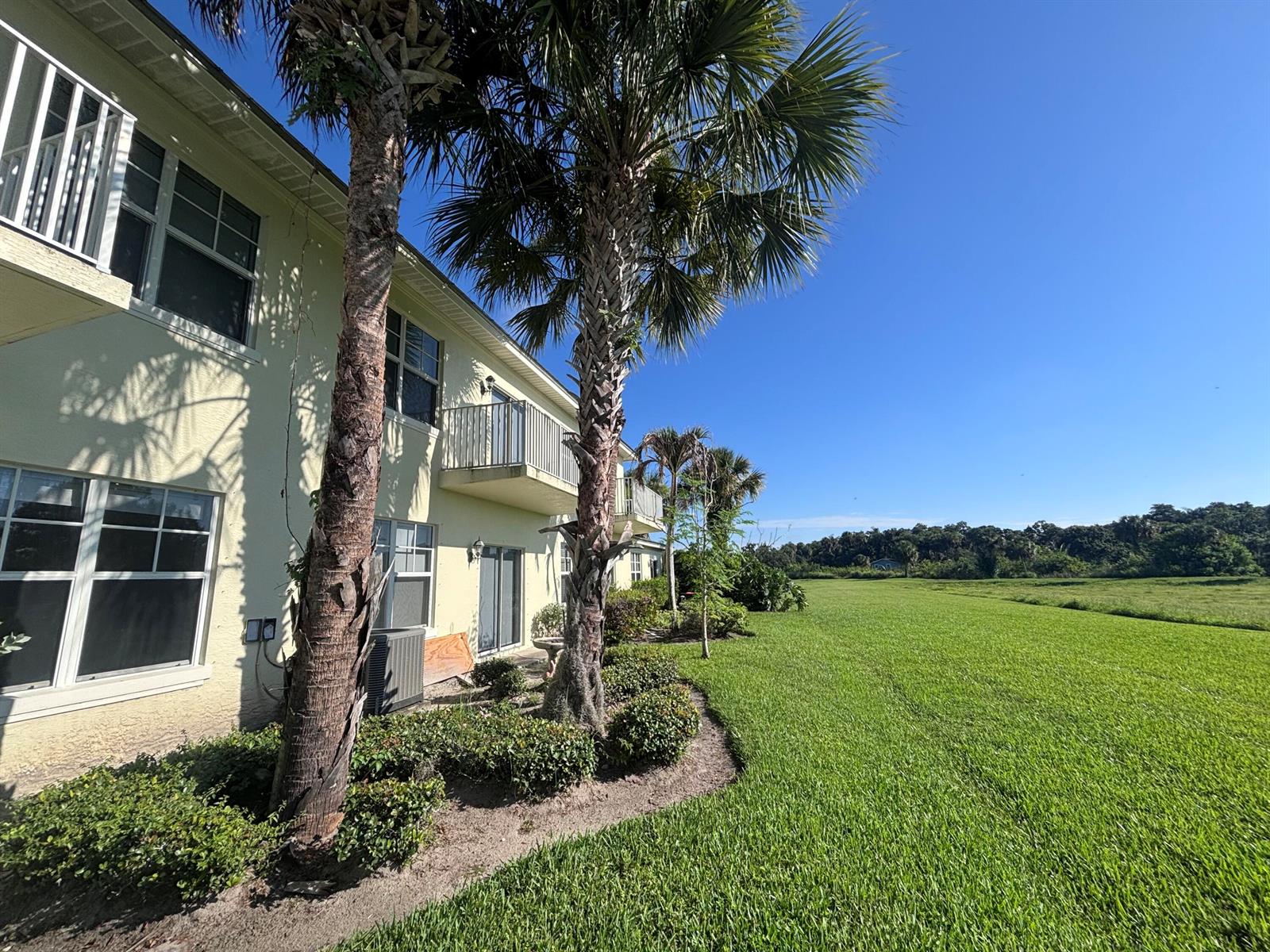 A multi-story apartment building with palm trees and a large grassy field under a blue sky — 3902 Sabal Way, Fort Pierce FL 34981, FORT PIERCE, FL