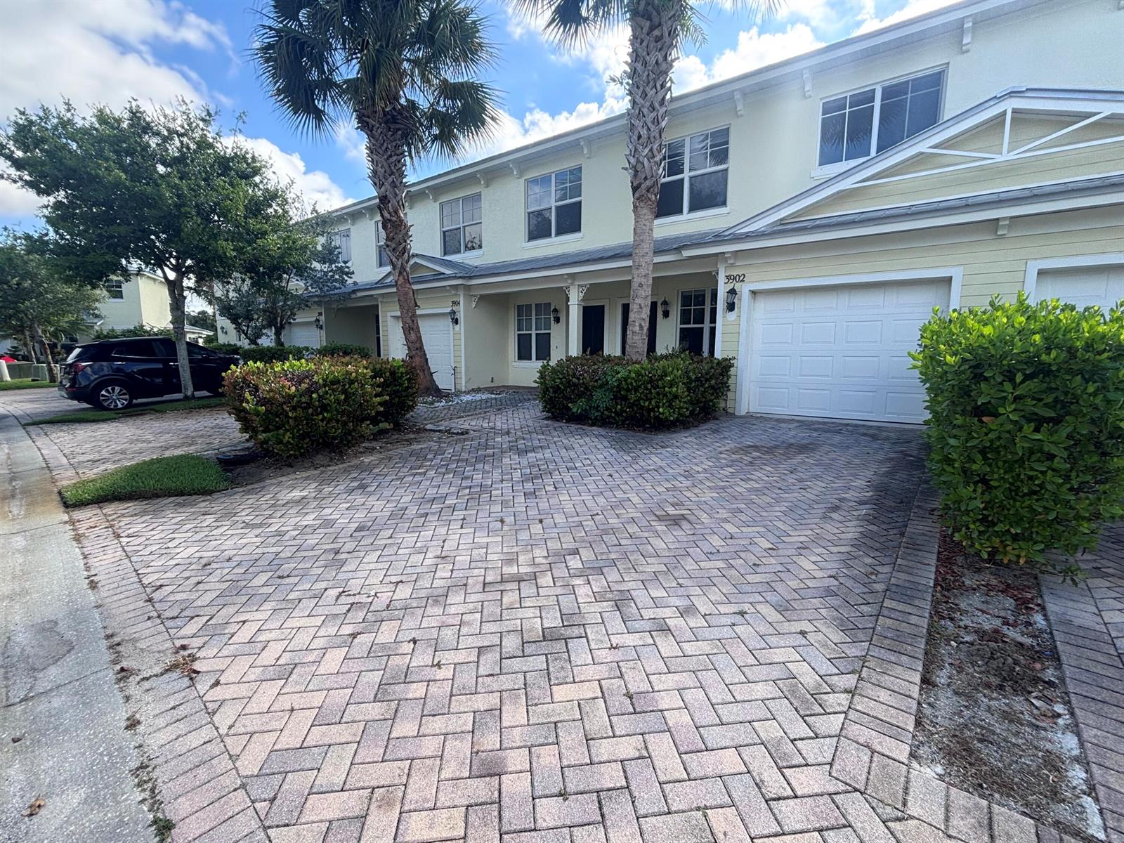 A two-story townhouse exterior features a paved driveway, white garage doors, and palm trees — 3902 Sabal Way, Fort Pierce FL 34981, FORT PIERCE, FL