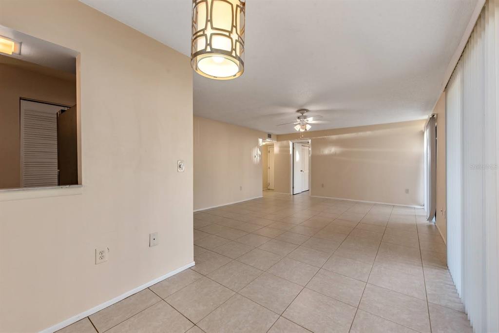 An empty living and dining area features beige tile flooring and a decorative pendant light — 2232 BAHIA VISTA STREET UNIT A1, SARASOTA, FL