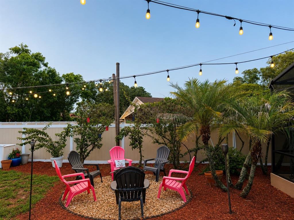 A backyard fire pit area features Adirondack chairs, string lights, and palm trees — 6203 COURTNEY COVE, APOPKA, FL