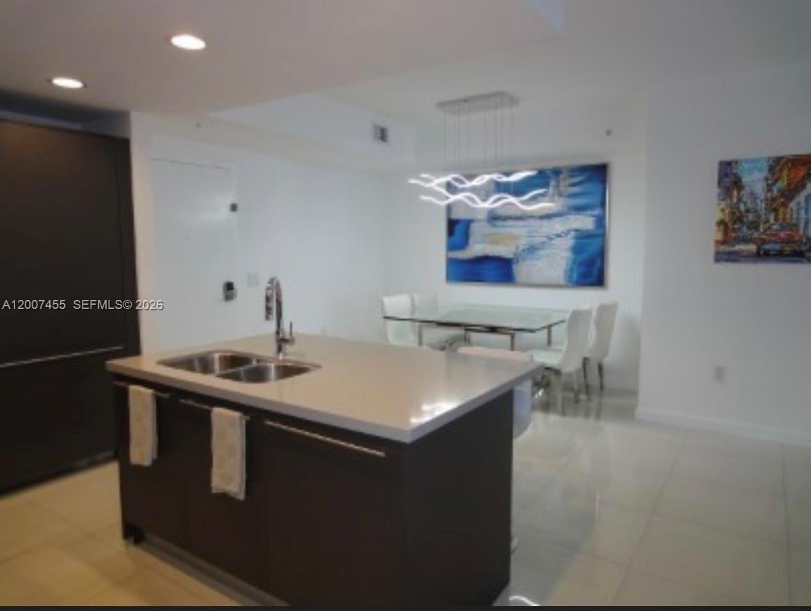 A kitchen island with a sink sits in front of a dining area with artwork — 7825 NW 107th Ave # 221, Doral FL 33178, DORAL, FL