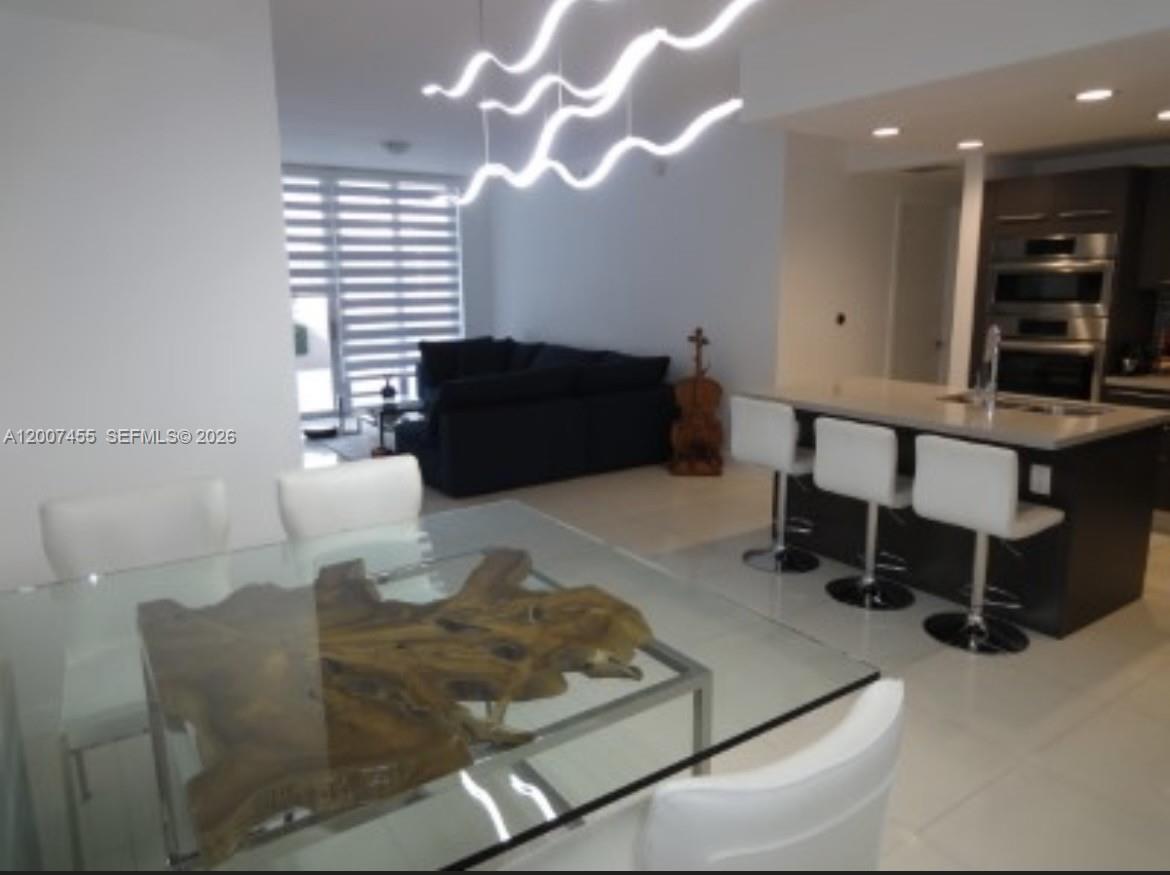A modern open-concept living area features a glass dining table, kitchen island, and white chairs — 7825 NW 107th Ave # 221, Doral FL 33178, DORAL, FL
