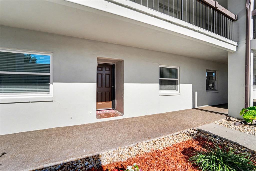 A ground-level exterior view of a building with a brown door and two windows — 5197 SILENT LOOP UNIT 121, NEW PORT RICHEY, FL