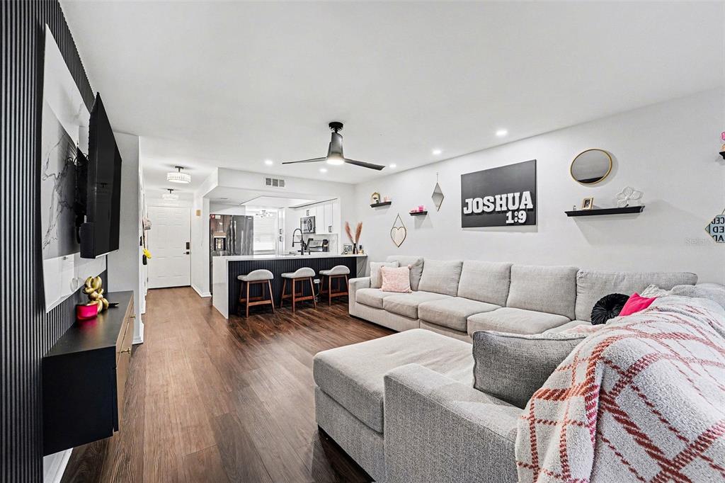 A living room with wood floors, a sectional sofa, and an open kitchen with bar seating — 5197 SILENT LOOP UNIT 121, NEW PORT RICHEY, FL
