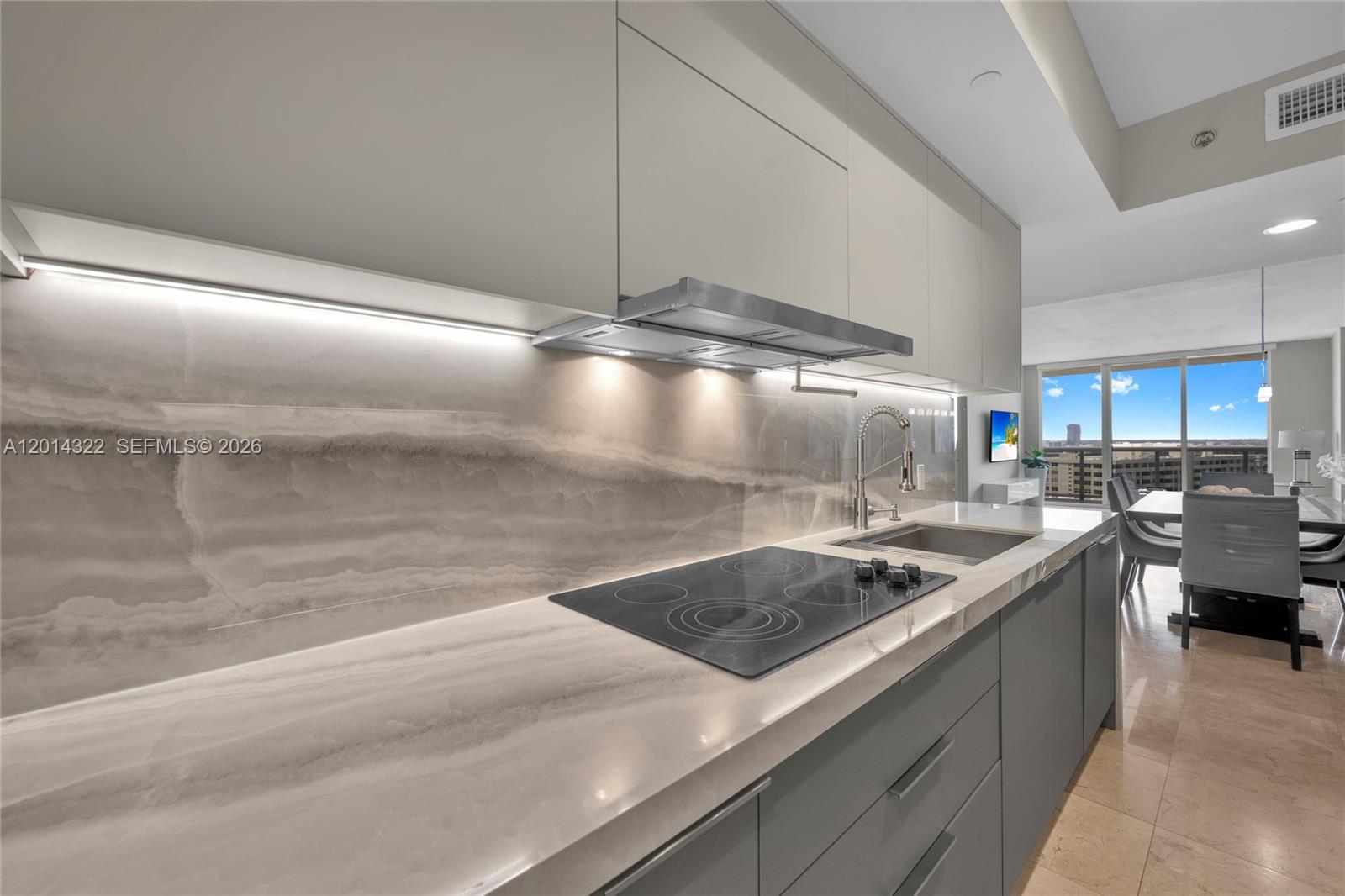 A modern kitchen features gray flat-panel cabinets, a stone countertop, and a matching slab backsplash — 1800 S Ocean Dr # 2007, Hallandale Beach FL 33009, HALLANDALE BEACH, FL
