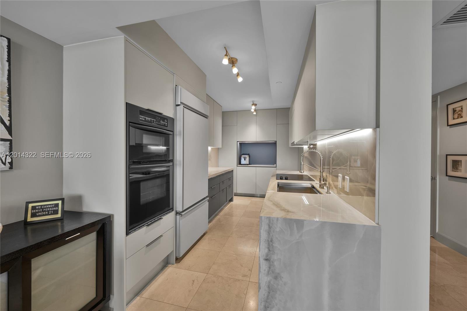 A modern kitchen features light cabinetry, stone countertops, a double wall oven, and tile flooring — 1800 S Ocean Dr # 2007, Hallandale Beach FL 33009, HALLANDALE BEACH, FL