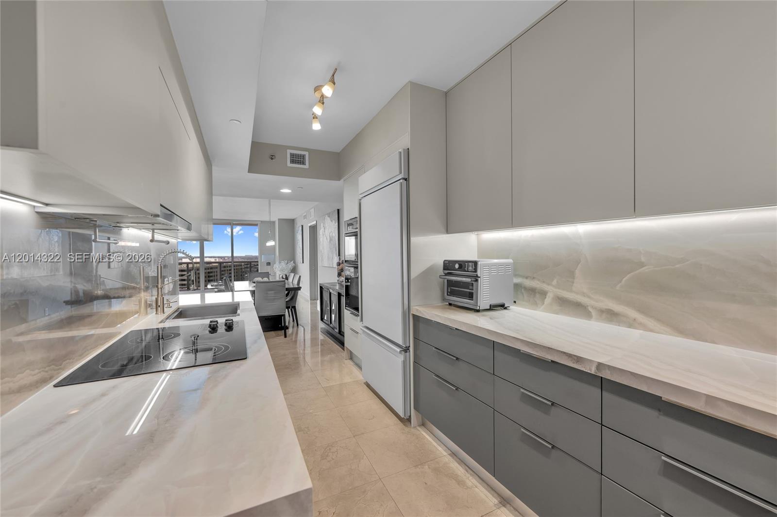 A modern kitchen features gray cabinetry, marble countertops, and a matching stone backsplash — 1800 S Ocean Dr # 2007, Hallandale Beach FL 33009, HALLANDALE BEACH, FL