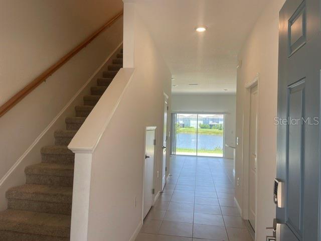 An entryway features carpeted stairs with a wooden railing and a view of a lake — 5730 ARCHIPELAGO, NOKOMIS, FL
