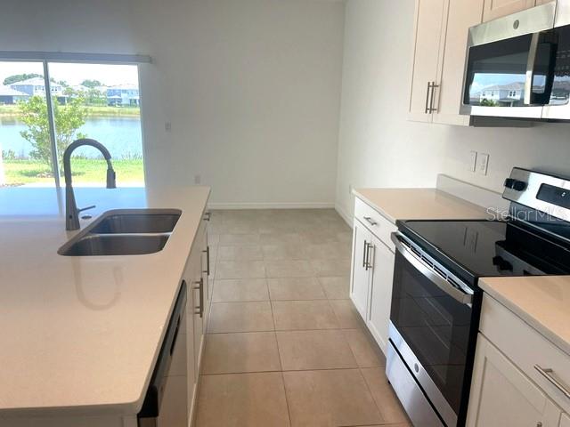 A kitchen features white cabinets, stainless steel appliances, a quartz island, and a water view — 5730 ARCHIPELAGO, NOKOMIS, FL