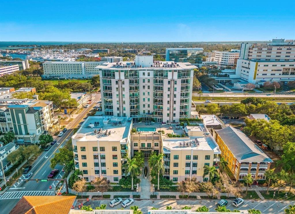 An aerial view of a multi-story apartment complex with a pool and surrounding city buildings — 400 4TH AVENUE S UNIT 408, ST PETERSBURG, FL