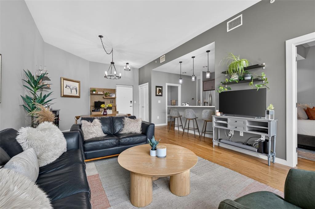 A living room with a black leather sofa, round wooden coffee table, and open kitchen — 400 4TH AVENUE S UNIT 408, ST PETERSBURG, FL