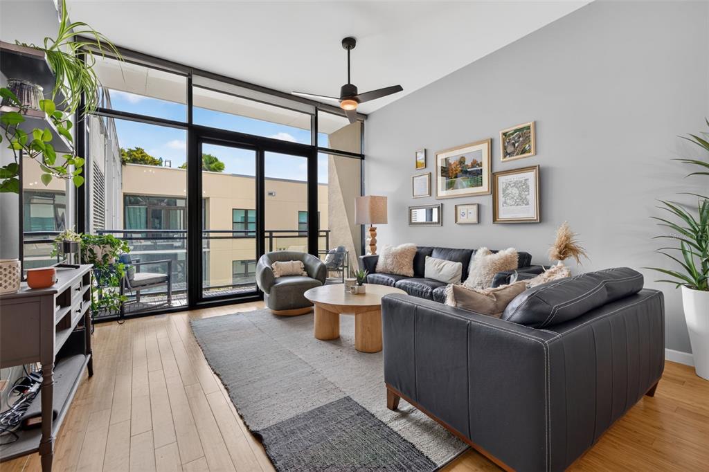 A modern living room features a dark leather sofa, wood coffee table, and floor-to-ceiling windows — 400 4TH AVENUE S UNIT 408, ST PETERSBURG, FL