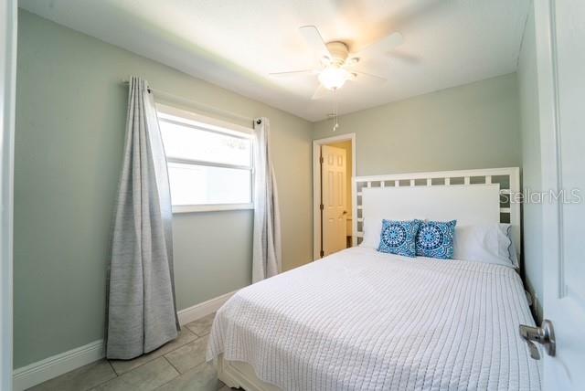 A bedroom with light green walls, a white bed, and a ceiling fan — 4825 FLORAMAR TERRACE, NEW PORT RICHEY, FL