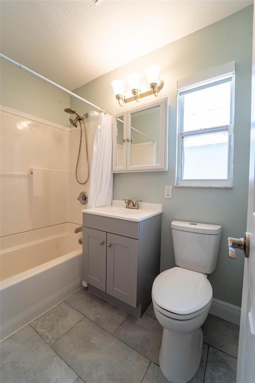 A bathroom features a gray vanity, a white toilet, and a shower-tub combination — 4825 FLORAMAR TERRACE, NEW PORT RICHEY, FL