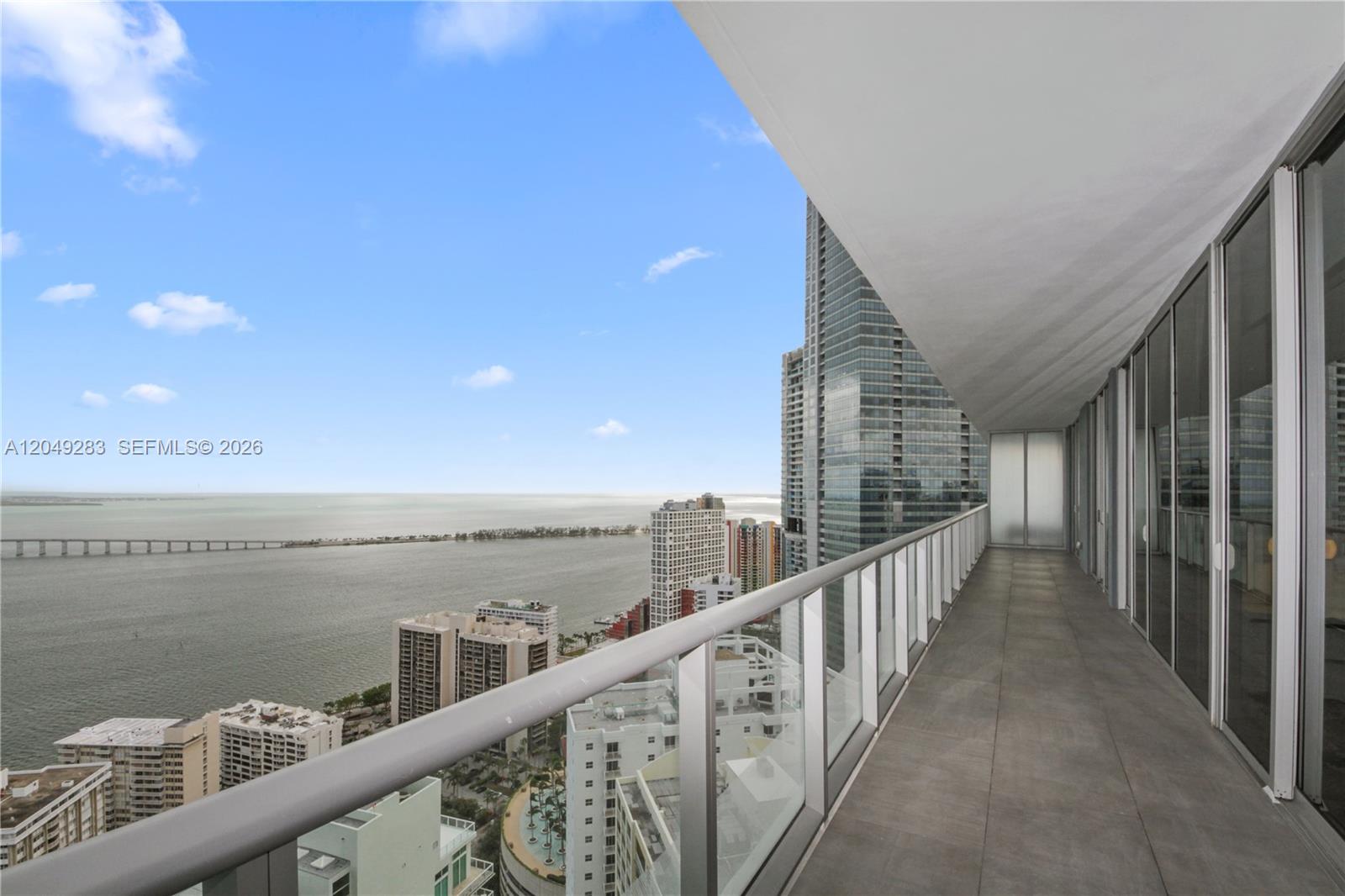 A high-rise balcony with a glass railing overlooks a bay, a bridge, and city buildings — 1300 Brickell Bay Dr # 4102, Miami FL 33131, MIAMI, FL