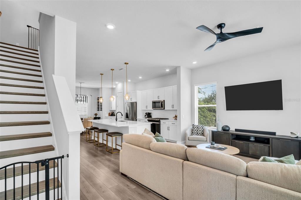 An open-concept living room and kitchen feature light wood floors, white cabinetry, and a staircase — 2851 1ST AVENUE S, ST PETERSBURG, FL