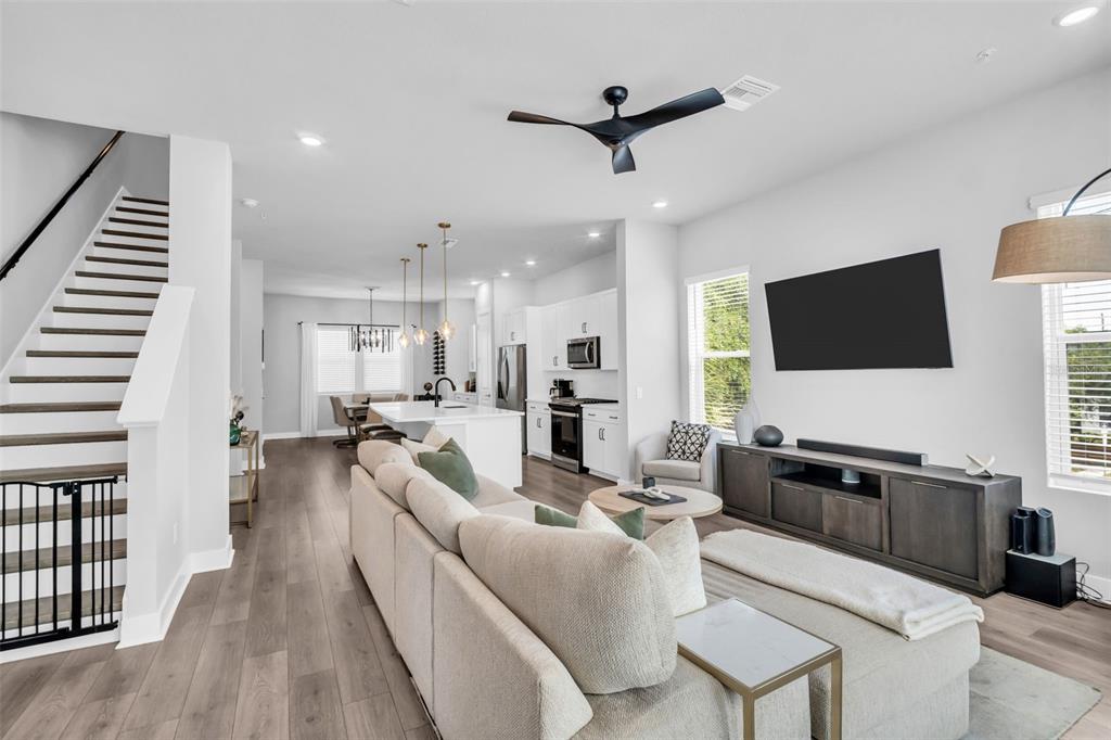 An open-concept living room and kitchen feature light wood flooring, a sectional sofa, and stairs — 2851 1ST AVENUE S, ST PETERSBURG, FL