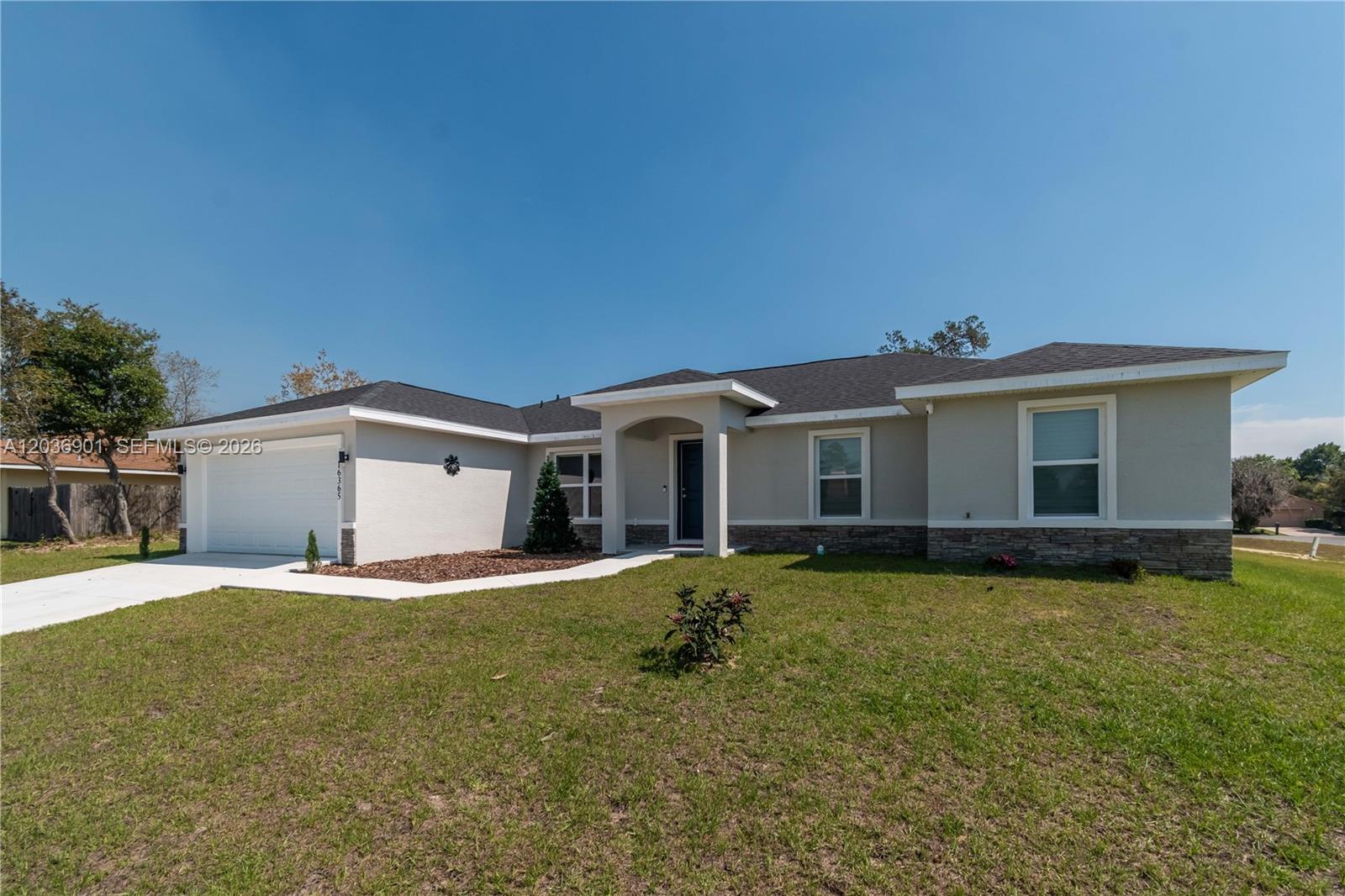 A single-story house with a beige stucco exterior, stone accents, and a two-car garage — 16365 SW 47 Terrace, Ocala FL 34473, OCALA, FL